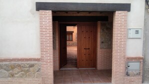 Une entrée d’immeuble avec une porte en bois, des murs en briques et un sol carrelé.