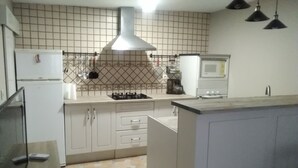 Une cuisine avec des meubles blancs, une cuisinière à gaz, un four à micro-ondes et un réfrigérateur.