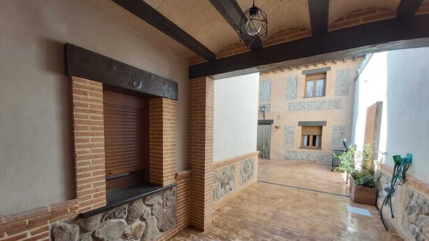 Une cour spacieuse avec un plancher en bois, des murs en pierre et un bâtiment en briques en arrière-plan.