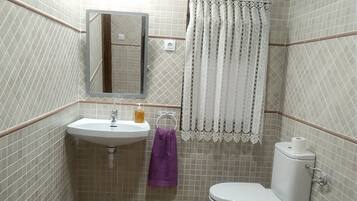 Een badkamer met een wastafel, spiegel, toilet en betegelde wanden.