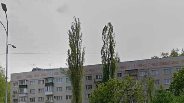 A multi-story residential building with balconies, a parking lot, and a street with a car. - OK Apartment (Kyiv)