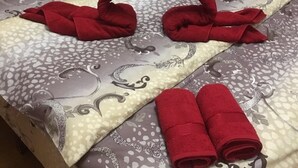 A bed with a patterned bedspread and two red towels folded into animal shapes. - OK Apartment (Kyiv)