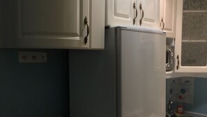 A compact kitchen with white cabinets, a built-in refrigerator, and a small countertop. - OK Apartment (Kyiv)