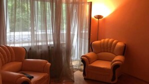 A room with two leather armchairs, a floor lamp, and a window with sheer curtains. - OK Apartment (Kyiv)