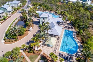 An aerial view of a resort with a large swimming pool, multiple guest villas, and a well-maintained landscape with palm trees. - 3,000+ Sq Ft! 5 Bikes! 3 King Suites- Serenity Pond at NatureWalk on 30A (Santa Rosa Beach)