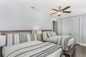 Ein Schlafzimmer mit zwei Betten, einem Deckenventilator und einer Tür.
