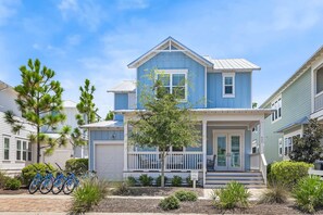 Une maison à deux étages avec un porche à l’avant, un garage et une pancarte « À vendre ».