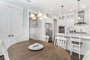 A modern kitchen with white cabinetry, stainless steel appliances, and pendant lighting.