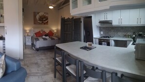 A compact living space with a sofa, a dining area, a kitchen, and a bedroom. - Self Catering Fully Equipped Cottage set in a leafy suburb (Plumstead)