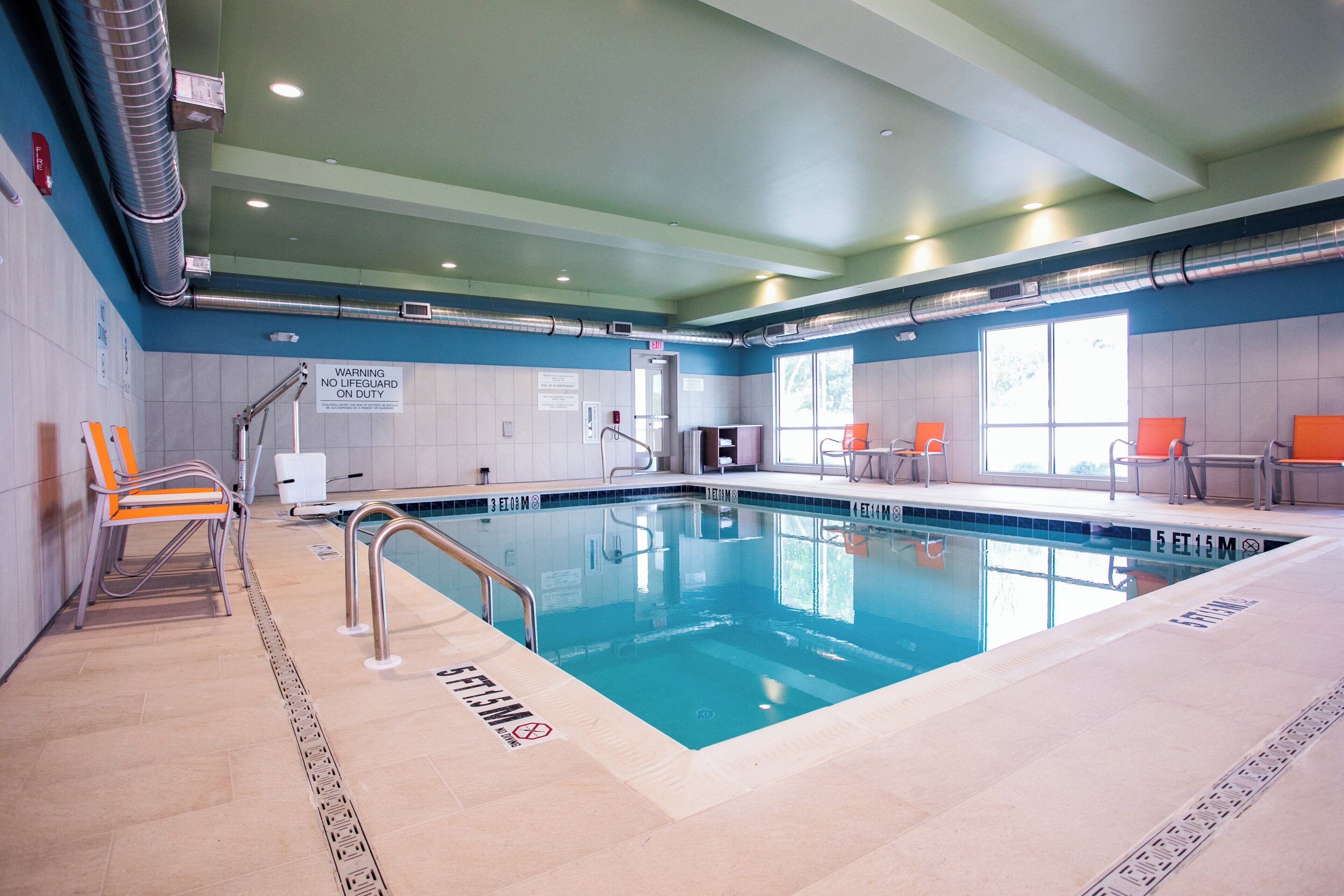 Une piscine intérieure avec des couloirs clairement délimités, des panneaux de signalisation de sécurité et un poste de surveillance pour le sauveteur.