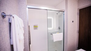 A modern bathroom with a glass-enclosed shower, a towel rack, and a wooden door. - Holiday Inn Express & Suites Rehoboth Beach by IHG (Rehoboth Beach)
