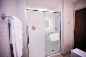 A modern bathroom with a glass-enclosed shower, a towel rack, and a wooden door.