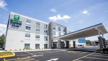 Un bâtiment de l’hôtel Holiday Inn Express & Suites, doté d’un parking couvert et surplombant un ciel dégagé.