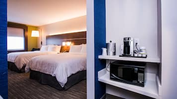 Ein Hotelzimmer mit zwei Betten, einer Mikrowelle, einer Kaffeemaschine und einer Lampe.