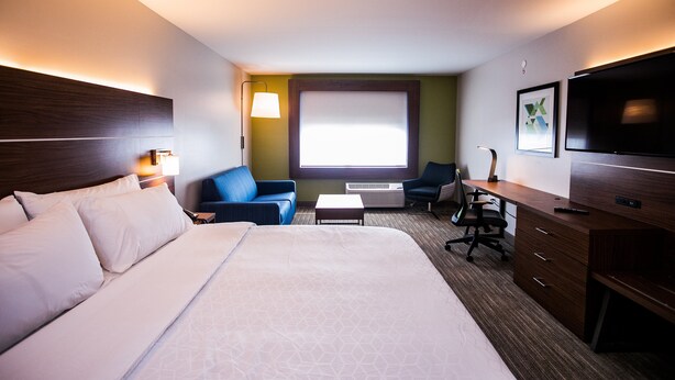 A hotel room with a large bed, a desk, a chair, a TV, and a window with blinds. - Holiday Inn Express & Suites Rehoboth Beach by IHG (Rehoboth Beach)