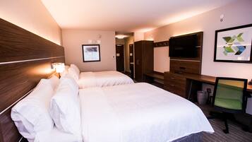 A hotel room with two beds, a desk, a chair, a TV, and a framed picture on the wall.