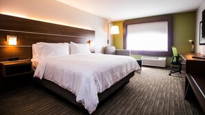 A hotel room with a large bed, bedside tables, a desk, and a window with blinds. - Holiday Inn Express & Suites Rehoboth Beach by IHG (Rehoboth Beach)