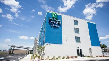 Edificio de Holiday Inn Express & Suites con fachada azul y blanca, un estacionamiento y cielo despejado.