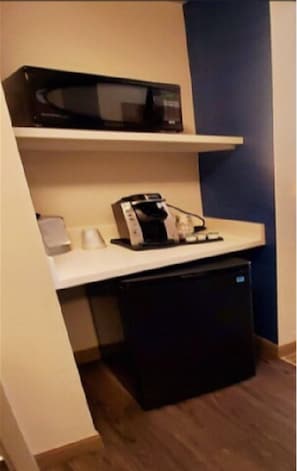 A compact kitchenette with a microwave, coffee maker, and a small refrigerator.