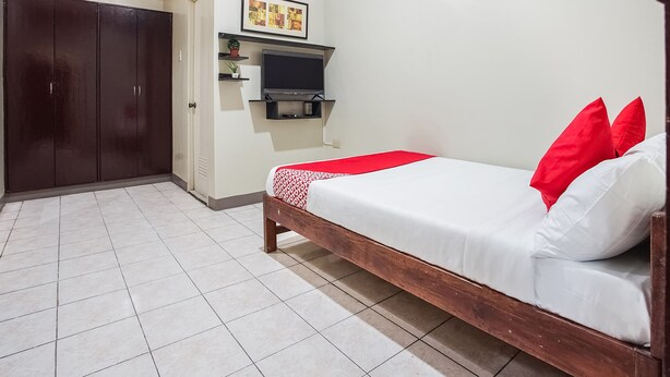 A bedroom with a bed, a wardrobe, a TV, and a framed picture on the wall. - OYO 522 Guadalupe Nuevo Building (Makati)