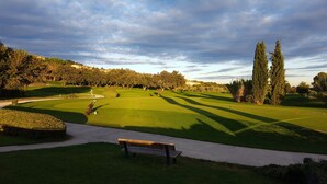 A golf course with a walking path, a bench, and trees in the background. - Golf & Résidence de Nîmes Vacquerolles (Nîmes)