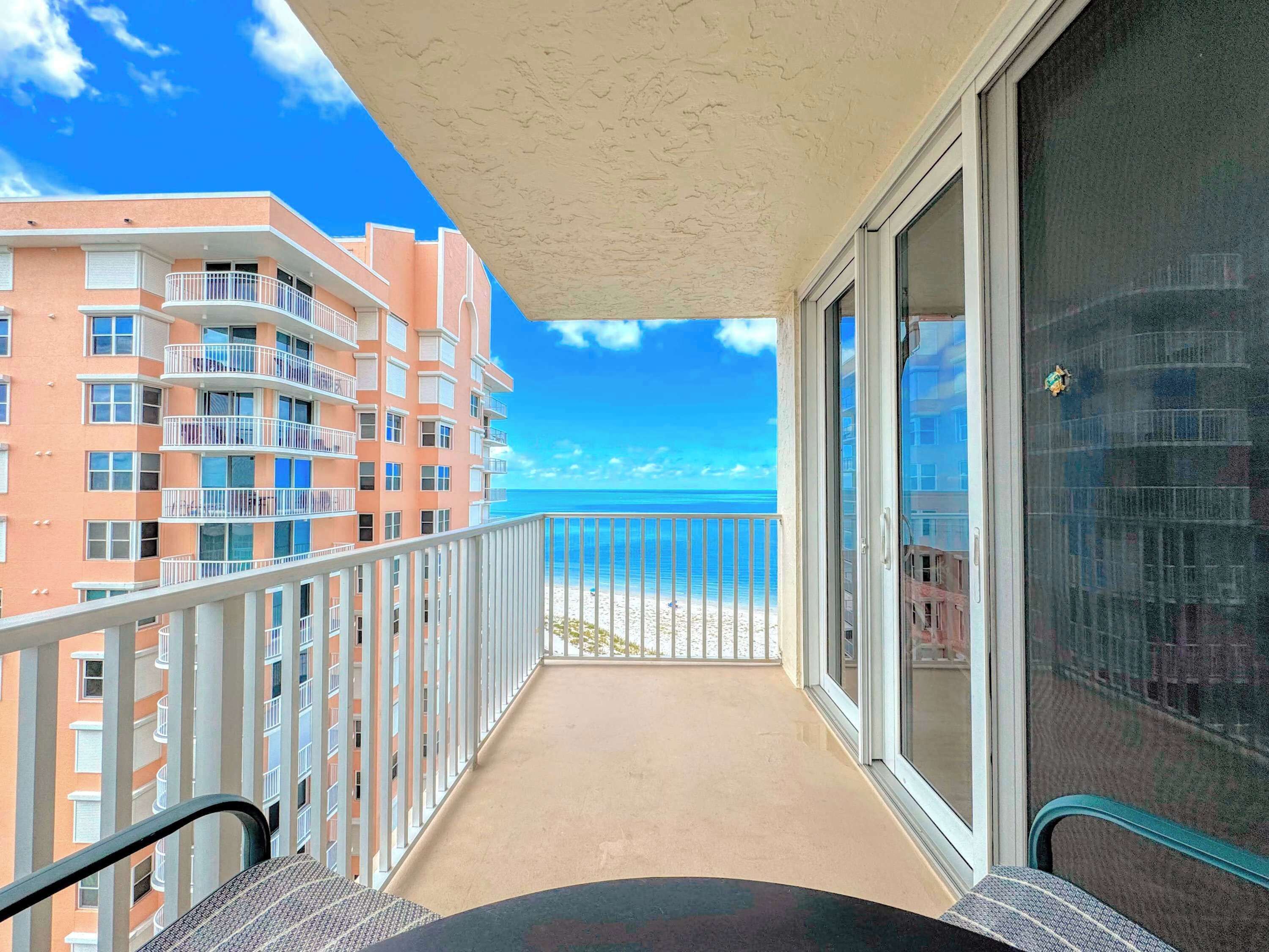 A balcony with a view of a beach and adjacent buildings.