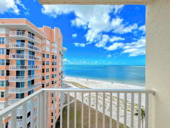 A multi-story building with balconies overlooking a beach.