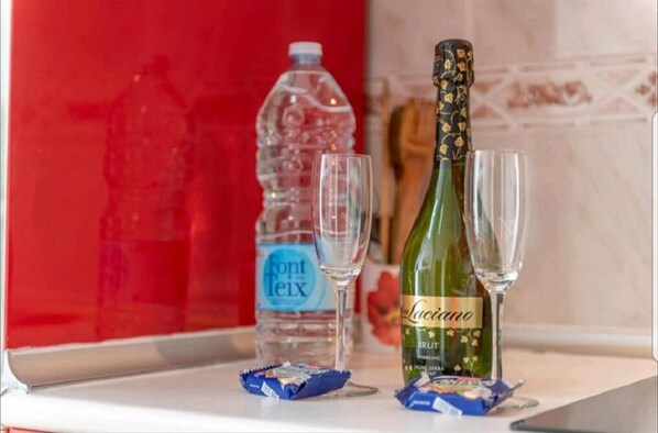 A bottle of Luciano Brut champagne, two glasses, and a bottle of Font Teix water on a counter. - Ronda Playa, apartment with pool just a step away from the sea. (Can Picafort)