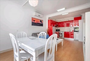 A modern kitchen with red cabinets and a dining area with a white table and chairs.