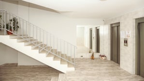 A modern interior with a staircase, elevators, and a hallway with marble flooring. - One Bedroom apartment for shopaholics (Tbilisi)