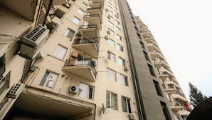 A high-rise building with multiple balconies, air conditioning units, and satellite dishes. - One Bedroom apartment for shopaholics (Tbilisi)