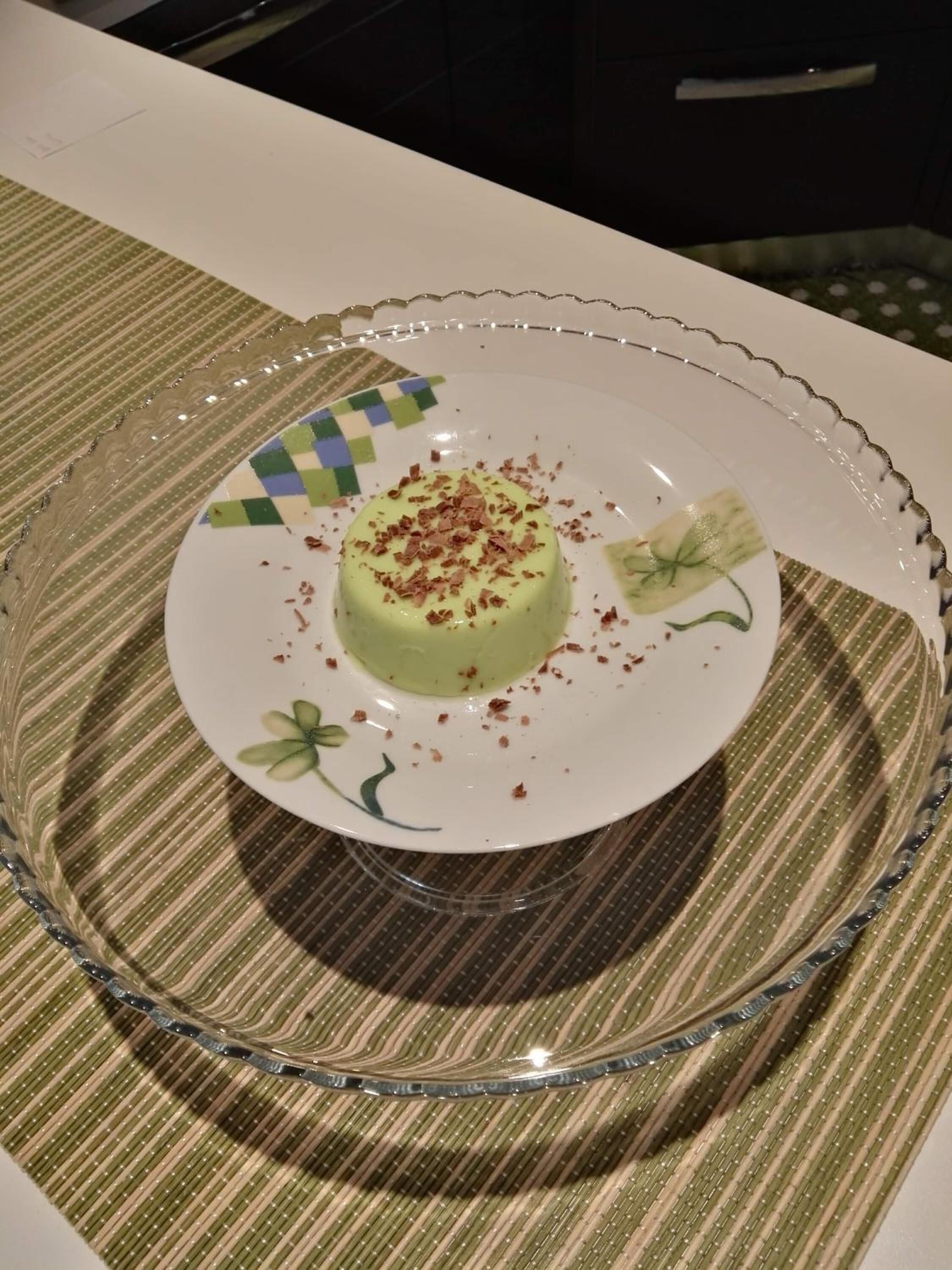A dessert on a glass plate with a scalloped edge, placed on a striped tablecloth.