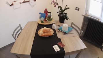 A dining table with a black tablecloth, bread, a bottle, a plant, and a menu.