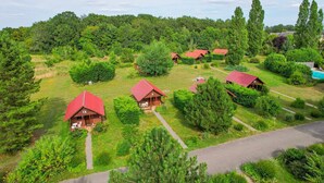 A cluster of cabins with red roofs, surrounded by lush greenery and a clear sky.