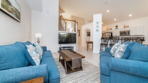 Relax in this stylish living room with two sofas, a flat-screen TV, and a kitchen area.
