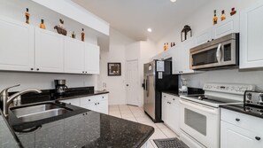 Enjoy cooking in this well-equipped kitchen with a stainless steel sink, refrigerator, microwave, oven, and toaster.