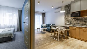 Une chambre d’hôtel moderne équip ée d’un lit, d’un canapé, d’un petit coin repas avec des tabourets et d’une cuisine avec un four à micro-ondes.