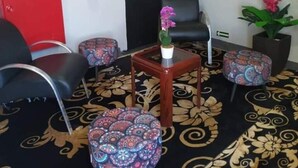 A waiting area with a red cabinet, a fire extinguisher, a framed menu, and a potted plant.