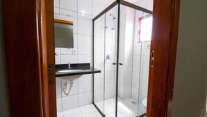 A bathroom with a glass shower enclosure, a sink with a black countertop, and a mirror above the sink.