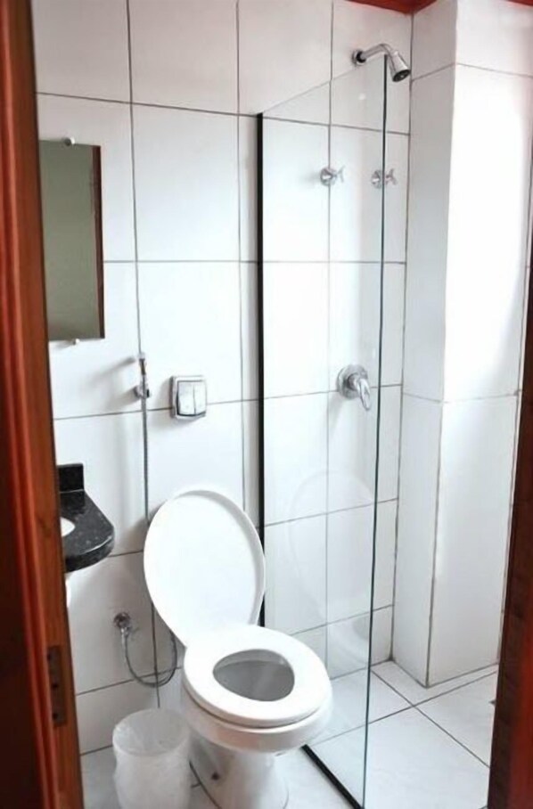 Uma casa de banho com sanita, chuveiro e lavatório.