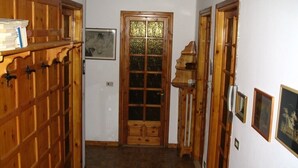 A narrow hallway with wooden paneling, a door with a window, and framed pictures on the walls. - Val di Cogne apartment (Vieyes)
