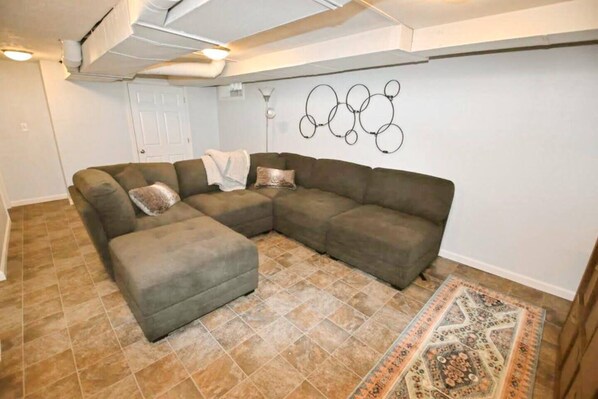 A living room with a sectional sofa, a patterned rug, and a wall art piece. - 2 blocks to ND! 4 bedroom 2 bath home(1217) (South Bend)