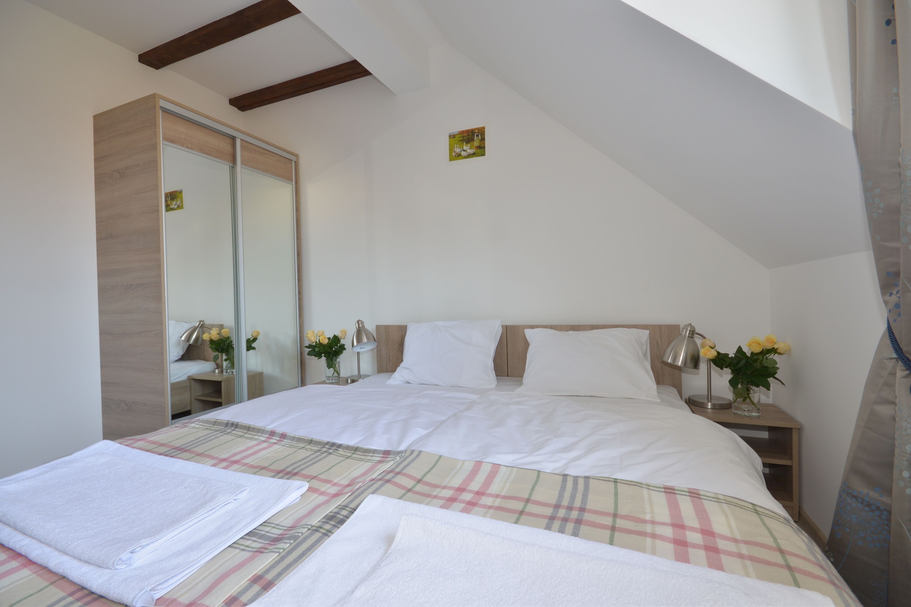 A bedroom with a bed, bedside tables, a mirror, and a window.