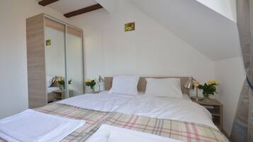 A bedroom with a bed, bedside tables, a mirror, and a window.