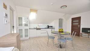 Una cocina moderna con armarios blancos, una mesa de comedor con cuatro sillas y un mueble para televisión.