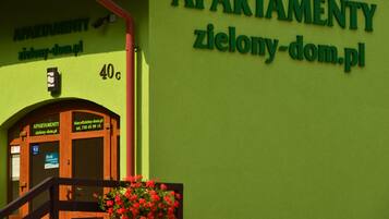 A building with a green facade and a sign reading "APARTMENTY zielony-dom.pl".