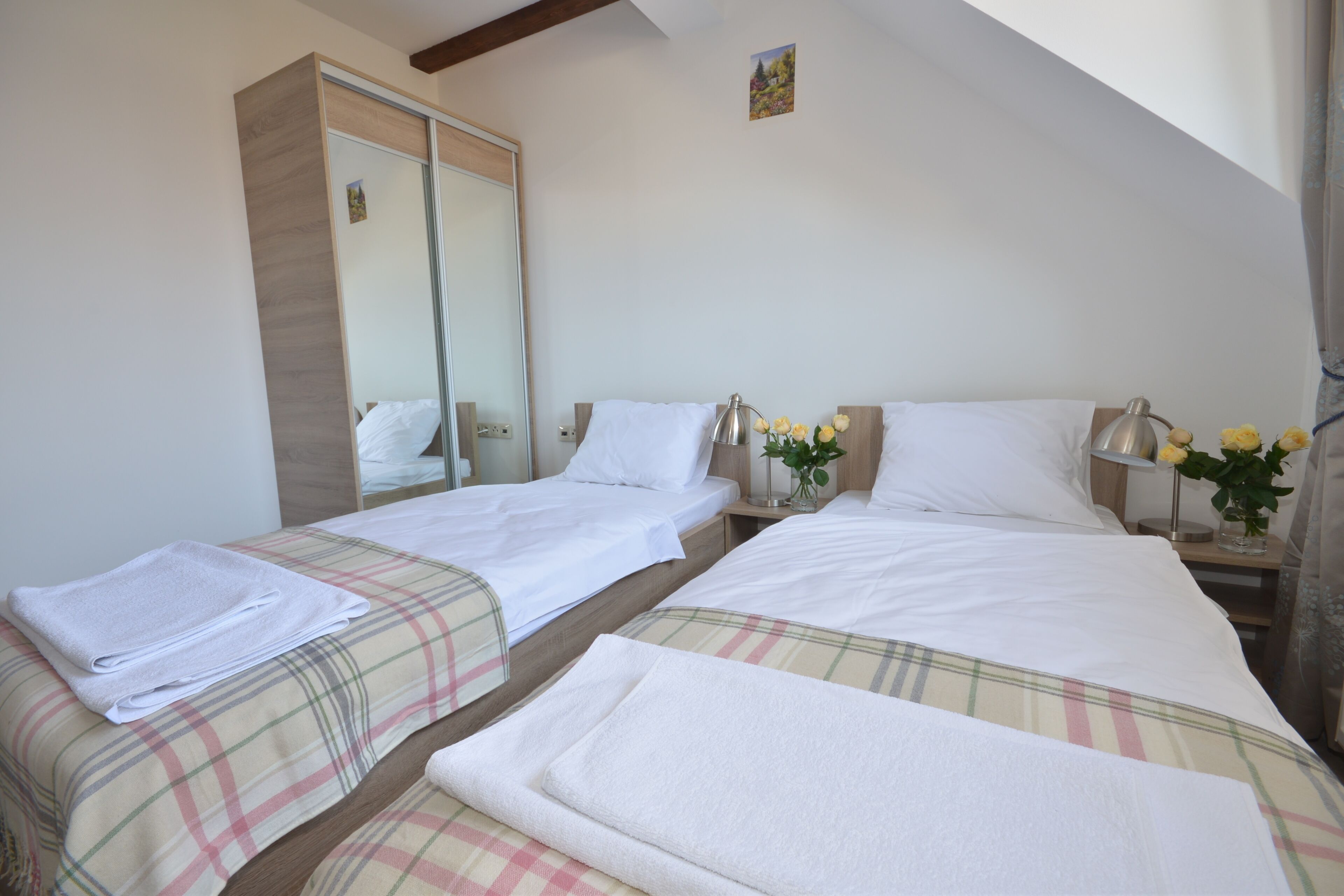 Una habitación de hotel con dos camas, un armario y una mesita de noche con una lámpara y flores.