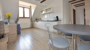 Una cocina moderna con comedor, vigas de madera en el techo y un ventanal que proporciona luz natural.