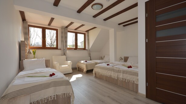 Un dormitorio con dos camas, una silla, una mesita y un ventanal grande.
