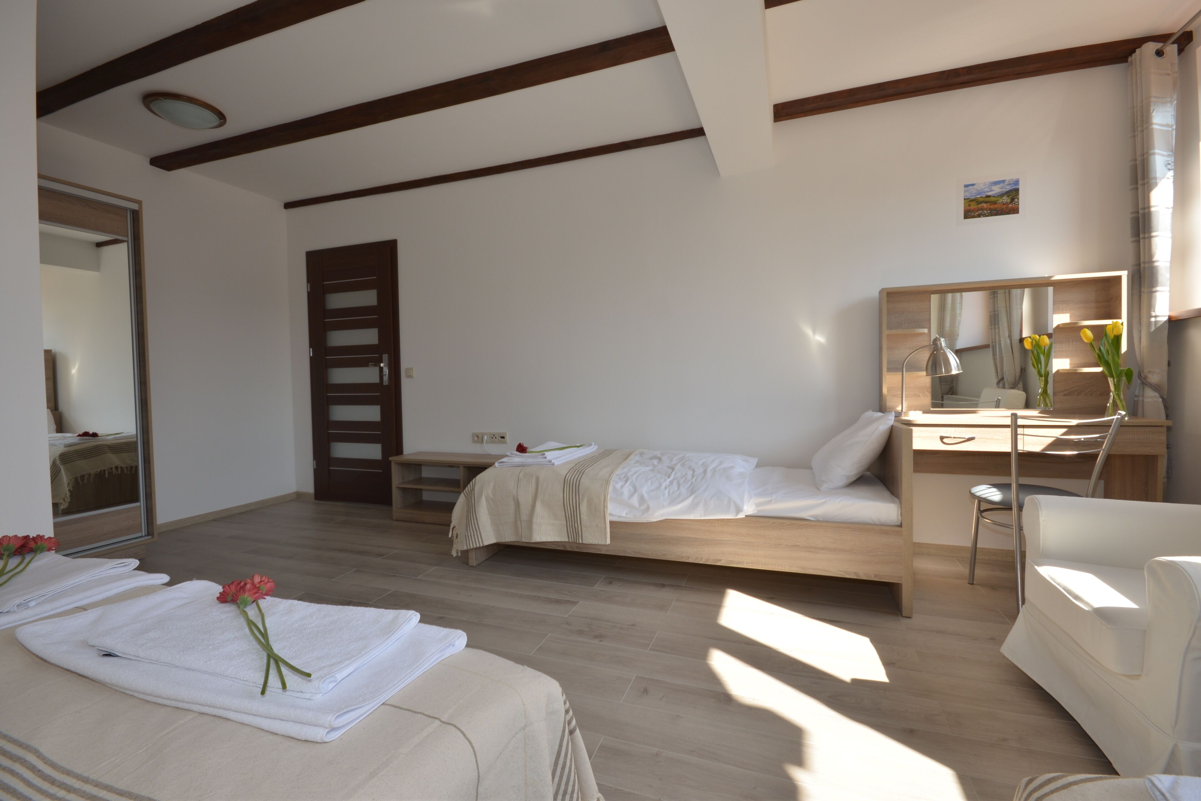 A bedroom with a bed, a desk, a chair, and a mirror.